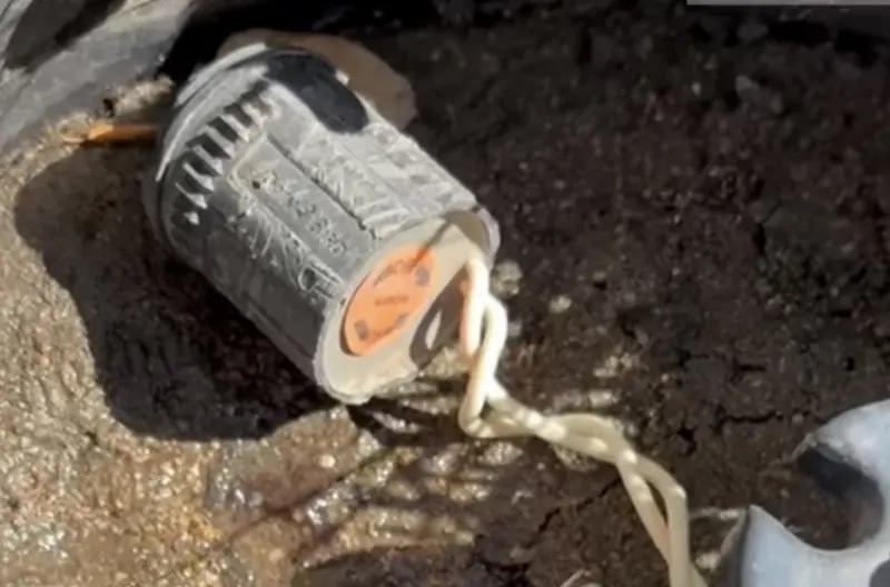 Sprinkler valve solenoid pulled from the soil next to wet ground
